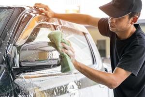 man een auto wassen bij carwash foto