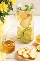 glas karaf met water, doordrenkt met citroen, limoen, gember en ingrediënten Aan licht achtergrond. foto