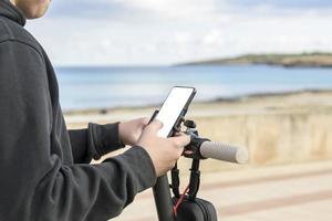 e-mobiliteit jong Mens met elektrisch scooter gebruik makend van smartphone app foto