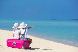 twee meisjes zittend op bagage op een strand foto