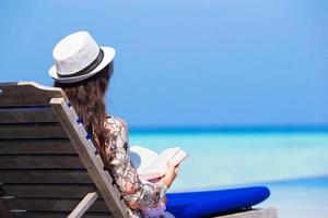 vrouw die een boek op het strand leest foto