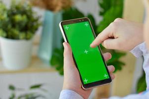 de kind is Holding een telefoon in zijn hand- met een groen scherm. foto