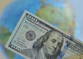 detailopname van een dollar Bill tegen de achtergrond van een wereldbol. de concept van globalisering van de wereld economie en de creatie van een single valuta ruimte. foto