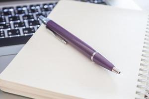 close-up van een notitieboekje en pen op laptop foto