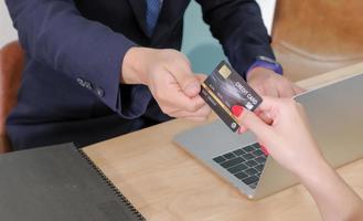 Aziatisch middelbare leeftijd mannetje teller onderhoud personeel ontvangen een bespotten omhoog credit kaart van jong vrouw klant voor maken betalingen. onderhoud bedrijf concept. foto