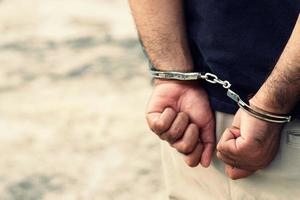 gevangene mannetje crimineel staand in handboeien met handen achter rug. foto