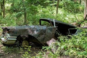 oud verroest auto verlaten in Woud met geweer kogel gaten foto