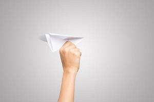 de hand van een vrouw houdt een papieren vliegtuigje op een witte achtergrond foto