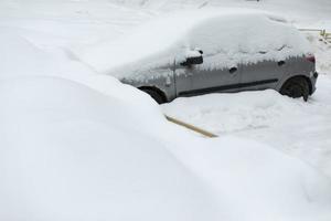 auto in winter in parkeren kavel. auto is geparkeerd in sneeuw. sneeuwbanken in parkeren kavel. foto