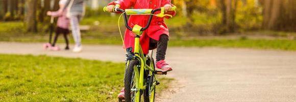 mooi glimlachen weinig meisje rijden fiets in een park foto