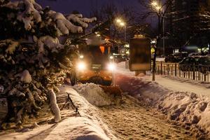 sneeuw blazer reinigt de weg in de stad foto