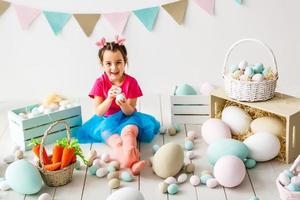 krijgen klaar naar Pasen. lief weinig meisje Holding een Pasen ei en glimlachen met decoratie in de achtergrond foto