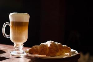 koffie latte en croissant Aan een houten tafel. kopiëren ruimte foto