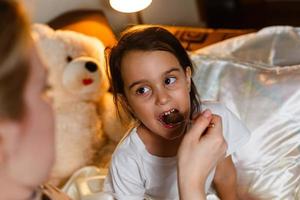 ziek meisje in bed met medicijnen met lepel foto