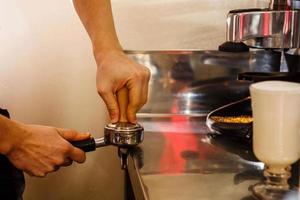 detailopname van mannetje barista hand- Holding grond koffie voor voorbereidingen treffen espresso, onderhoud en voorbereiding concept. foto