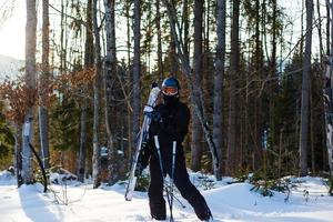 skiër klaar Holding skiën uitrusting met zon terug licht Aan ski helling - jong atleet in sneeuw bergen voor winter vakantie - sport concept en vakantie concept - focus Aan zijn gezicht - warm filter foto