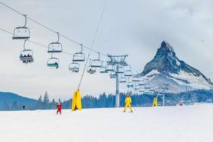 moeder en dochter hebben pret en aan het leren skiën maken eerste stappen met mama's ondersteuning Aan een ski winter toevlucht Bij berg heuvel. foto