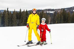 weinig meisje en een vrouw zijn skiën naar beneden een berg foto