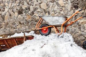 kruiwagen met sneeuw in een tuin in winter dag, gereedschap gedekt door sneeuw foto