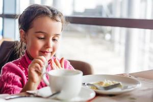 schattig weinig meisje drankjes thee in de ochtend- foto