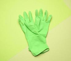 paar- van groen beschermend rubber handschoenen voor schoonmaak Aan een groen achtergrond foto