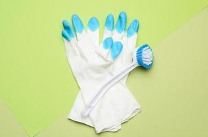 wit rubber handschoenen voor schoonmaak, borstels Aan een groen achtergrond foto