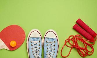 sportschoenen, springen touw en houten rackets voor tafel tennis Aan een groen achtergrond foto