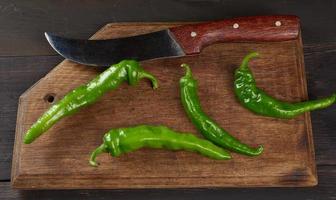 groen heet peper peulen Aan een bruin houten tafel foto