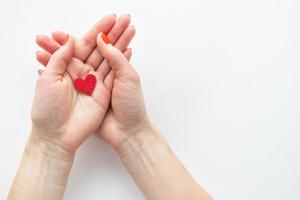 vrouw handen zijn Holding een klein rood hart. de concept van zorg en liefde. foto