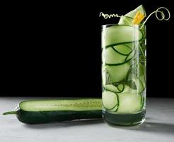 transparant glas met komkommer stukken, munt bladeren en mineraal water foto