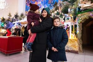 moeder met kinderen bezoek Kerstmis geboorte wieg tafereel in kerk. foto