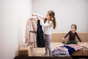 twee zussen zijn kiezen kleren van de garderobe Bij huis Aan de bank. foto