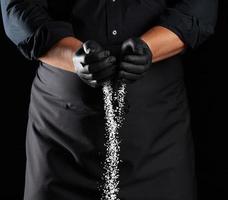 wit grof zout is gegoten van de chef-kok handpalmen, zwart achtergrond foto