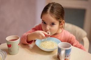 meisje heeft avondeten in keuken, eten bouillon. foto