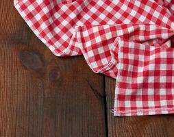 rood Wit textiel keuken handdoek Aan een bruin houten achtergrond van oud borden foto
