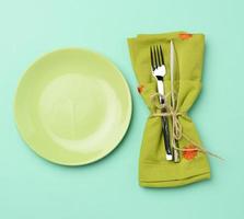 leeg ronde groen keramisch bord en metaal vork en mes, groen achtergrond foto
