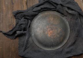 ronde bord en zwart keuken textiel handdoek gevouwen Aan een bruin houten tafel foto