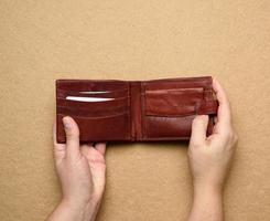 twee vrouw handen houden bruin leer Open portemonnee voor contant geld foto