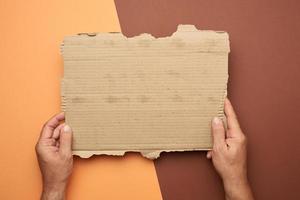 twee mannetje handen houden een blanco gescheurd stuk van bruin papier foto
