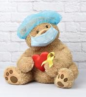 bruin teddy beer houdt in zijn poot een geel lint gevouwen in een lus foto