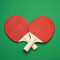 rood houten tafel tennis racket Aan groen achtergrond, paar- van ping pong sport- gereedschap foto