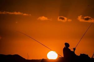 visvangst haspel over- de zonsondergang foto