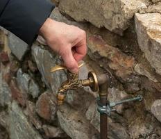 antiek messing water kraan net zo een bouwkundig monument. oud kraan met water Aan de straat. foto