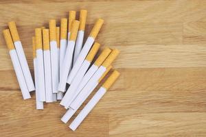 beeld van meerdere commercieel gemaakt sigaretten. stapel sigaret Aan houten donker achtergrond. of niet roken campagne concept, tabak. top visie foto