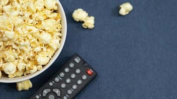 een kom van popcorn en afgelegen controle voor TV Aan een tafel houten achtergrond. concept vrije tijd en vermaak foto