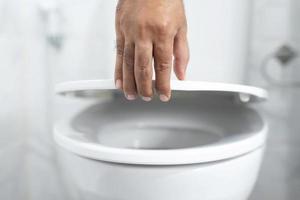 dichtbij omhoog hand- van een Mens sluitend de deksel van een toilet stoel. foto