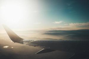 vliegtuigvleugel boven mistige bergen foto