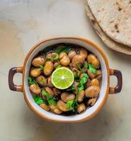 vol medames - schotel van Egyptische fava bonen met citroen ,komijn ,groente olie en gehakt peterselie, geserveerd met vlak brood Aan wazig marmeren achtergrond, populair veganistisch schotel gedurende de midden- oosten- foto