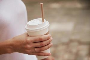 vrouw houdt papier koffie kop Bij stad straat foto