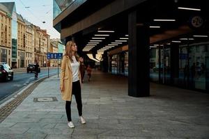 vrouw in jas wandelingen Bij stad stret foto